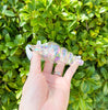 Side view of the clear iridescent seashell hand pipe on green background with natural lighting