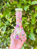 Green dried floral bong with pink and purple flowers on a green background