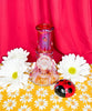 Red ladybug bong with ladybug charms on red background with white daisies.