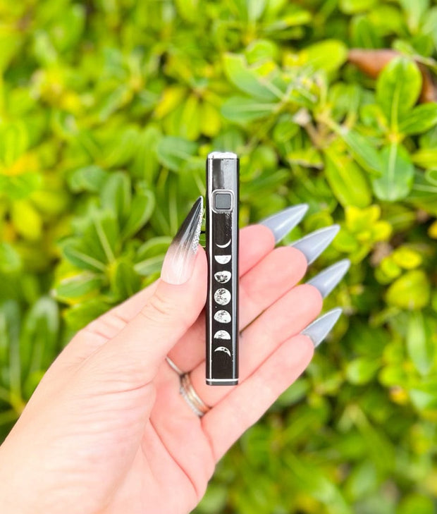 Hand holding a black crescent moon design 510 threaded battery vape pen