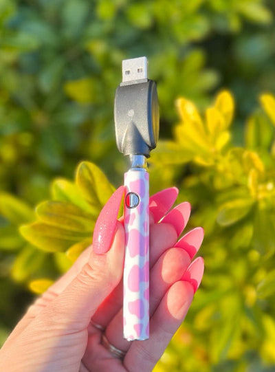 hand holding a pink cow print vape pen