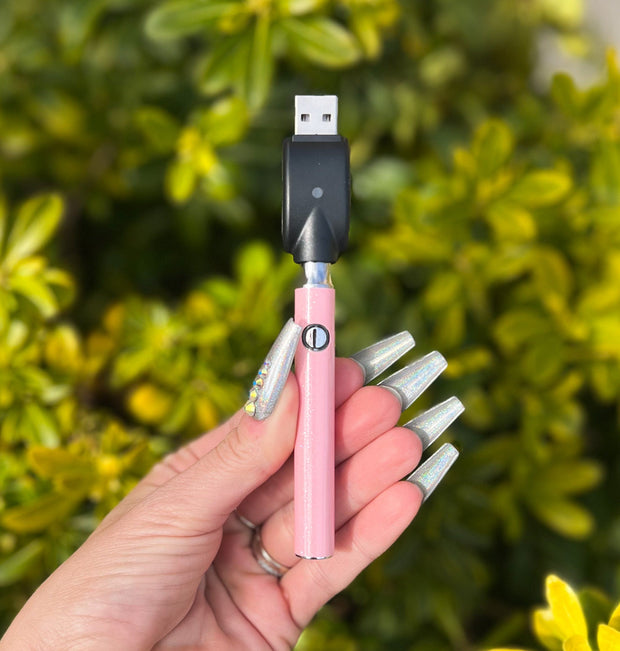 Baby pink glitter vape pen with pink crystal bottom on green background