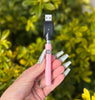 Baby pink glitter vape pen with pink crystal bottom on green background