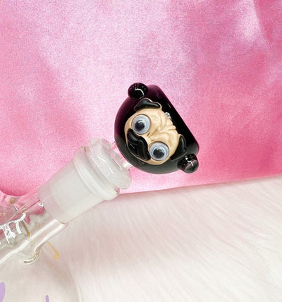 A black glass bowl designed to resemble a pug dog with a 14mm male joint, placed on a surface with a pink background.
